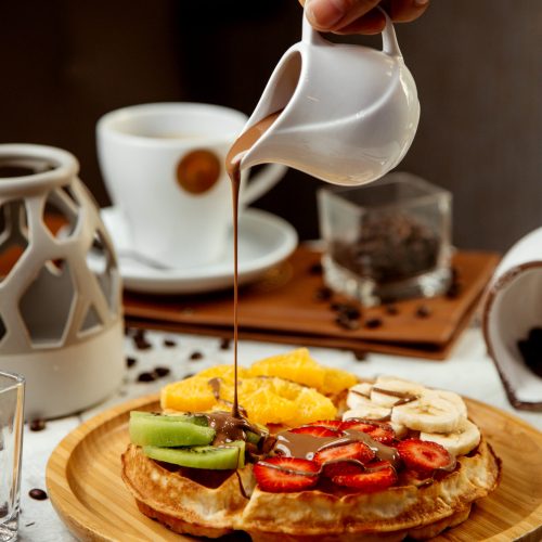 waffles topped with sliced fruits and hot chocolate